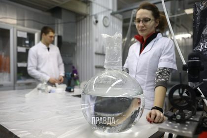 Сотрудники в лабораторных халатах с колбой в научной лаборатории